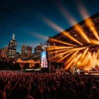 Crowd enjoying a live concert in Melbourne under stage lights with city skyline behind Crowd enjoying a live concert in Melbourne under stage lights with city skyline behind